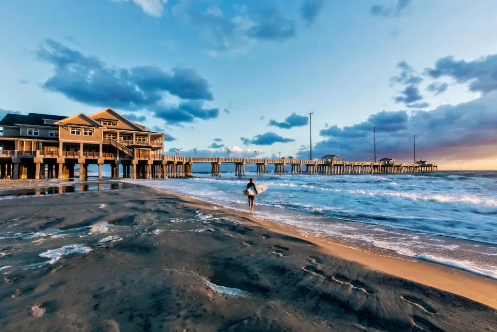 Surfer at sunrise at Jeanette's Pier in Nags Head, North Carolina