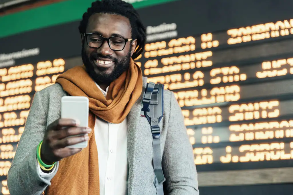 Man on cellphone in front of departures board