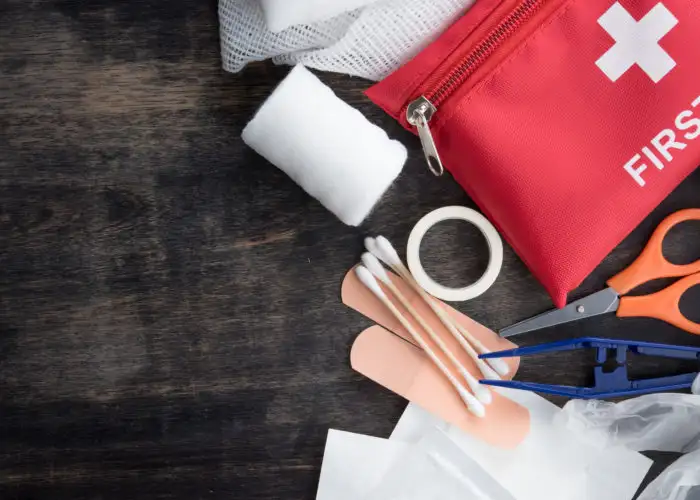 First aid kit and supplies on a dark wood backdrop