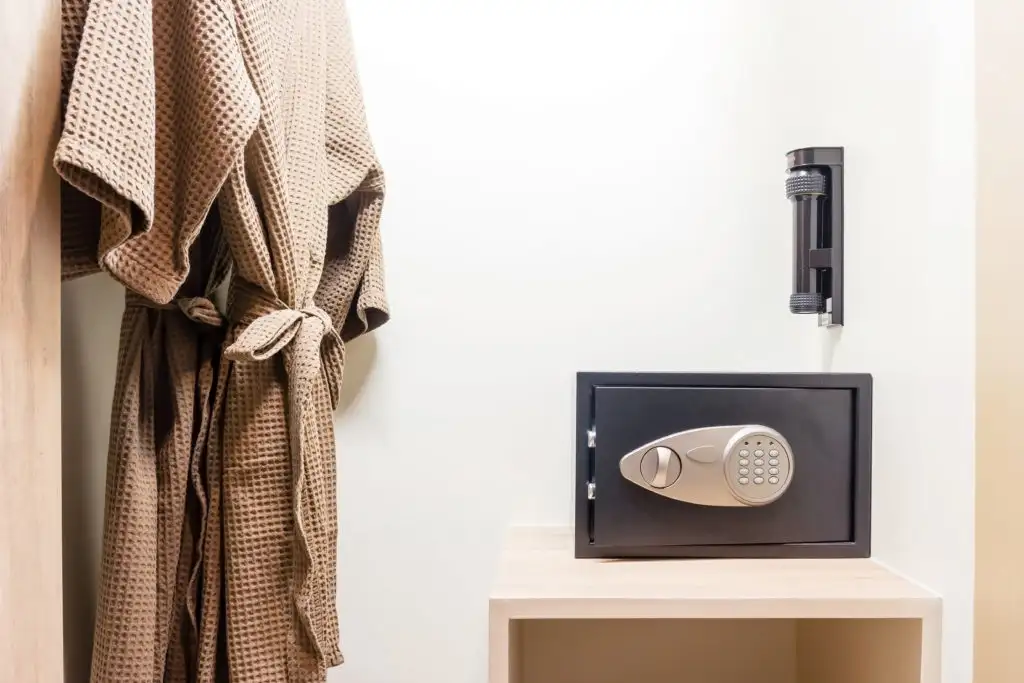 Hotel safe in a closet next to two hanging hotel robes