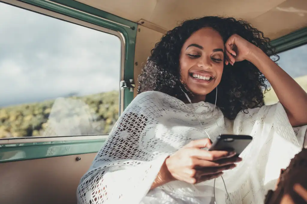 Woman listening to music on her phone in backseat of a car