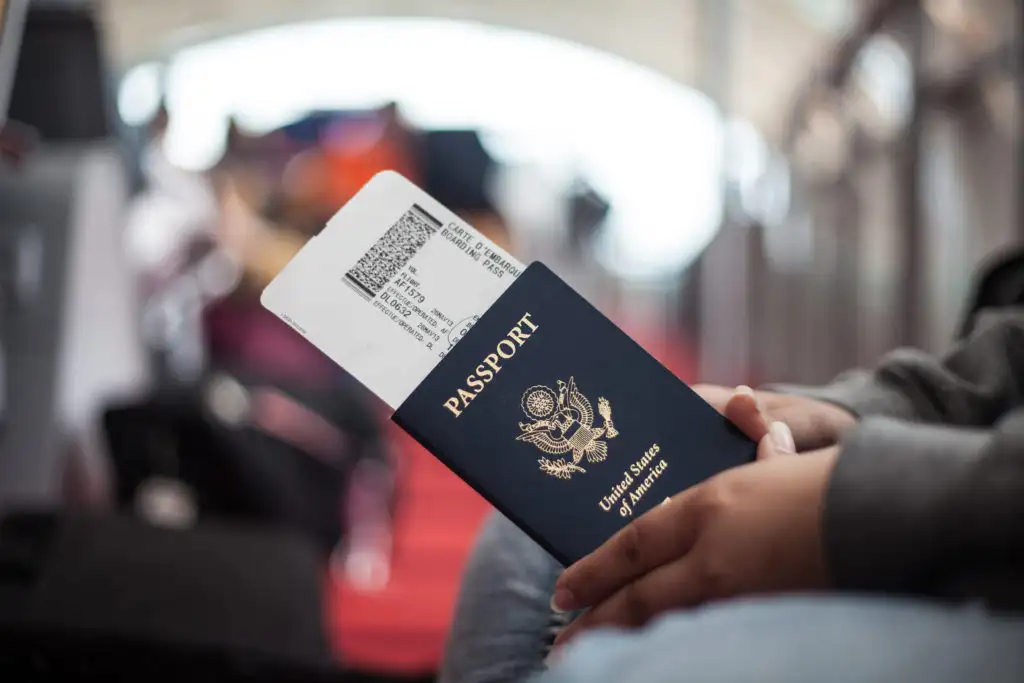 Close up of hands holding a passport and boarding passes in a busy airport