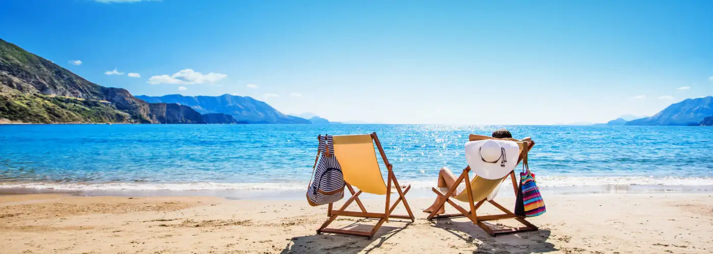 Person sunbathing on yellow beach chair on empty beach