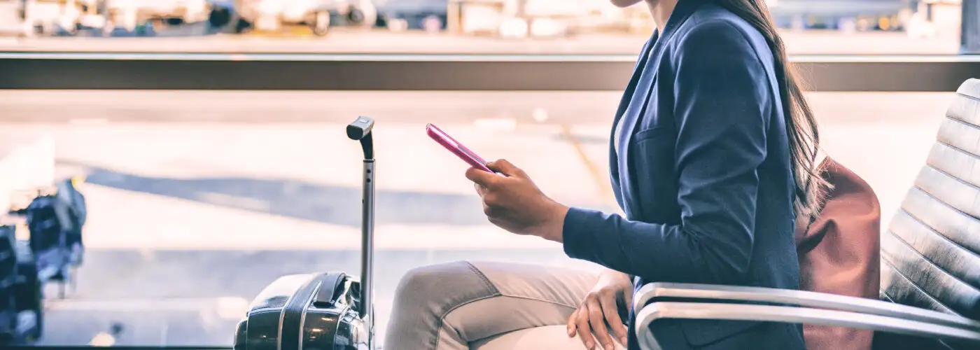 Close up of person looking at phone while waiting in an airport terminal