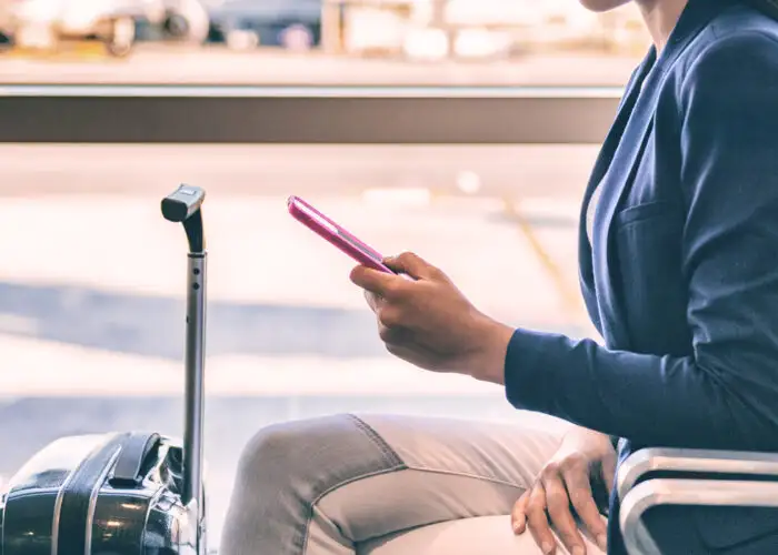 Close up of person looking at phone while waiting in an airport terminal