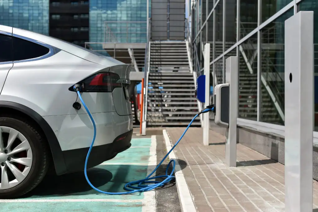 Small white electric car plugged into a charging station