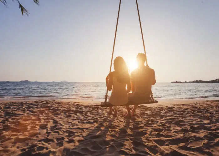 Silhouette of couple on swing on beach