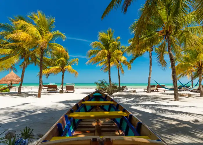 A colorful boat in the foreground of a beach with palm trees and ocean views