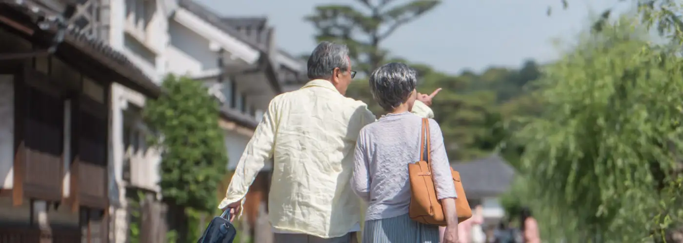 A couple carrying luggage and walking through a scenic destination