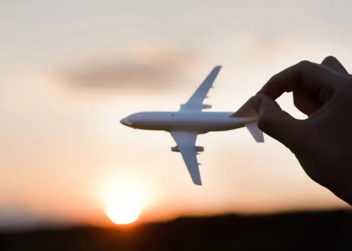 Person holding toy plane up against a sunset sky