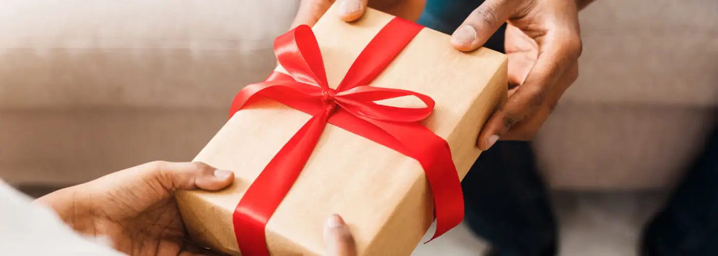 Two people exchanging a gift with a red ribbon