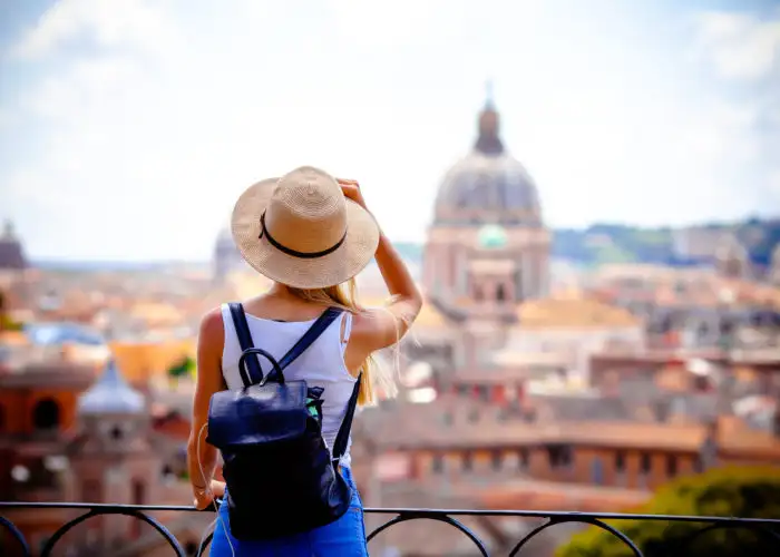 Woman standing on a balcony taking a photo of the Roman landscape