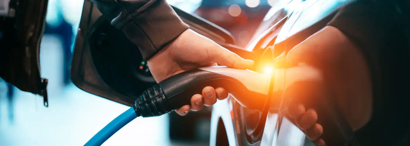 Close up of hand plugging in an electric car