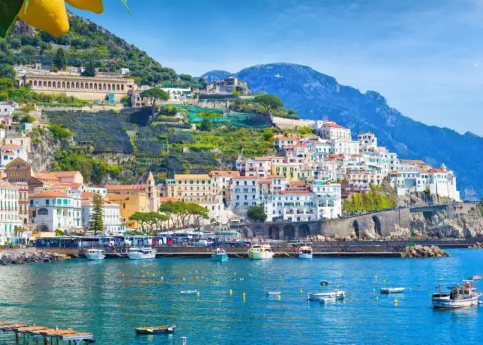 Panoramic view of beautiful Amalfi on hills leading down to coast, Campania, Italy. Amalfi coast is most popular travel and holiday destination in Europe. Ripe yellow lemons in foreground.