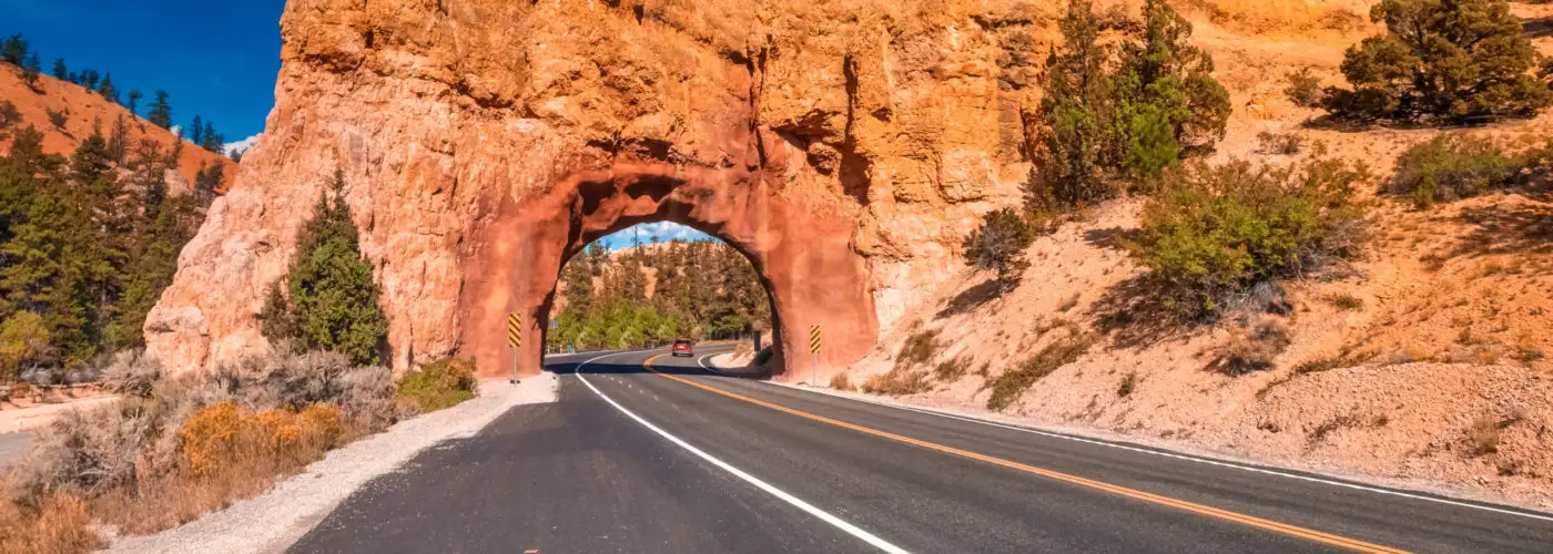 Road running under stone arch at the entrance of Bryce Canyon National Park