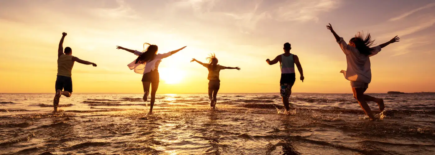 Silhouette of group of friends running into the ocean