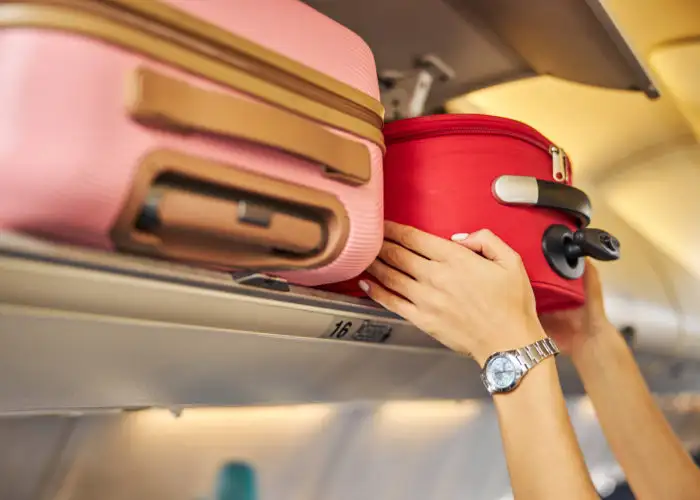 Person putting carry-on luggage in overhead bin