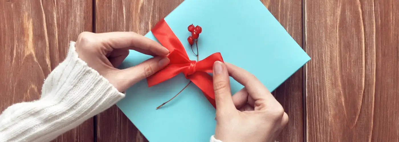 Aerial view of woman tying a red ribbon on a blue box