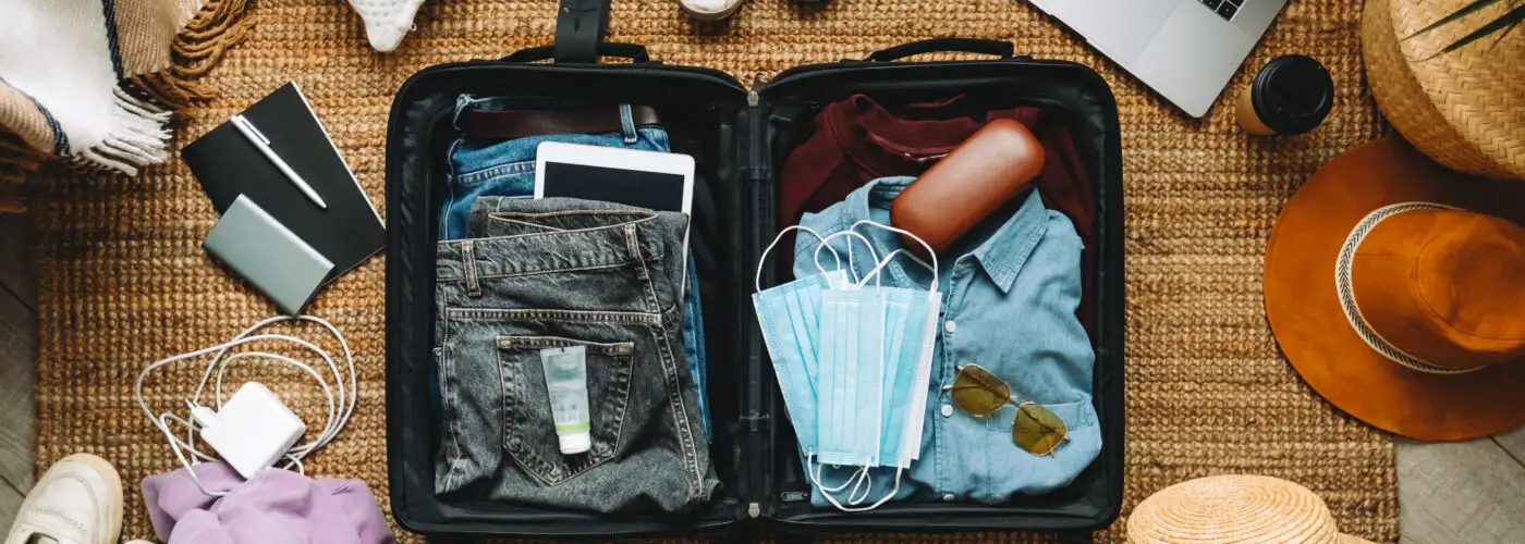 Overhead view of packing suitcase surrounded by other travel gear