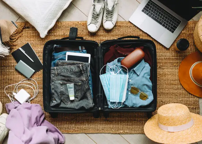 Overhead view of packing suitcase surrounded by other travel gear