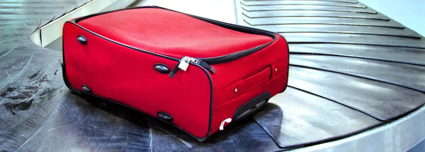 Single red suitcase on an otherwise empty baggage carousel