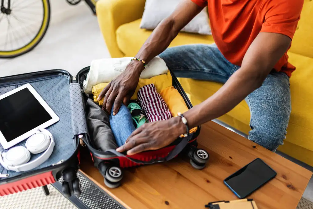 Close up of person's arms as they pack a well-organized carry-on suitcase