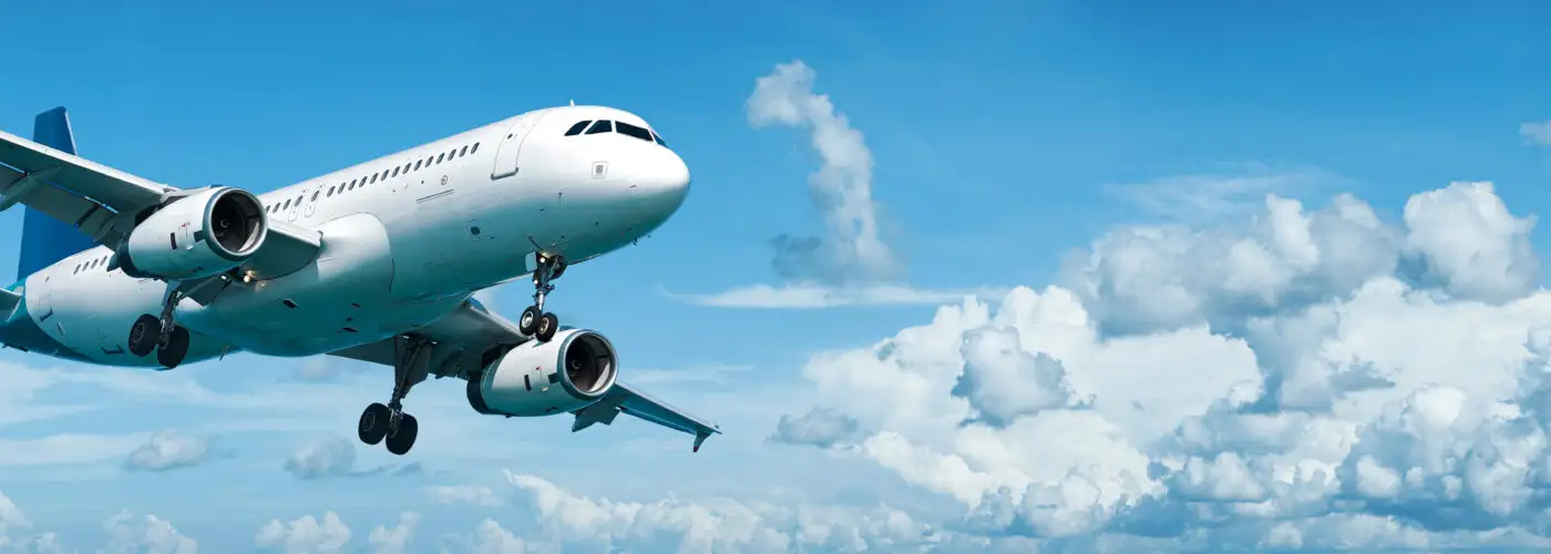 Airplane flying through a blue sky with white clouds