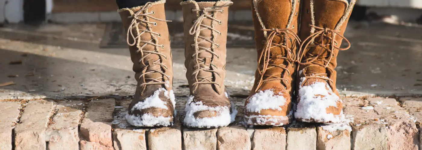 Close-up of people wearing winter boots with snow on them