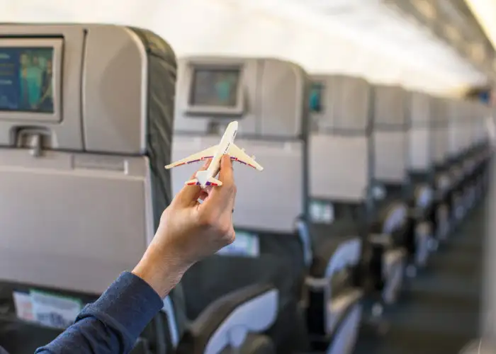 Close up of person's hand holding a model plane inside a real plane