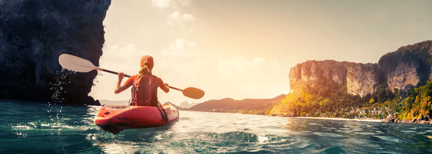 Woman kayaking in a canyon at sunset