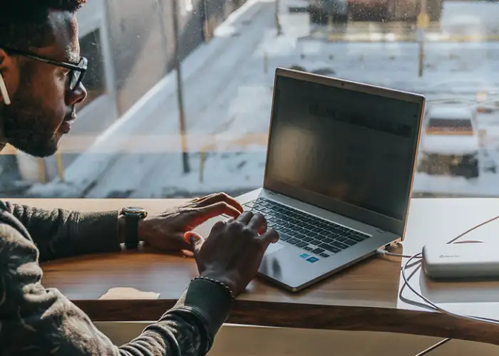 Man working in cafe with laptop plugged into a BioLite Charge Series portable charger