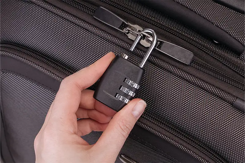 Close up of a person unlocking a suitcase with a luggage lock