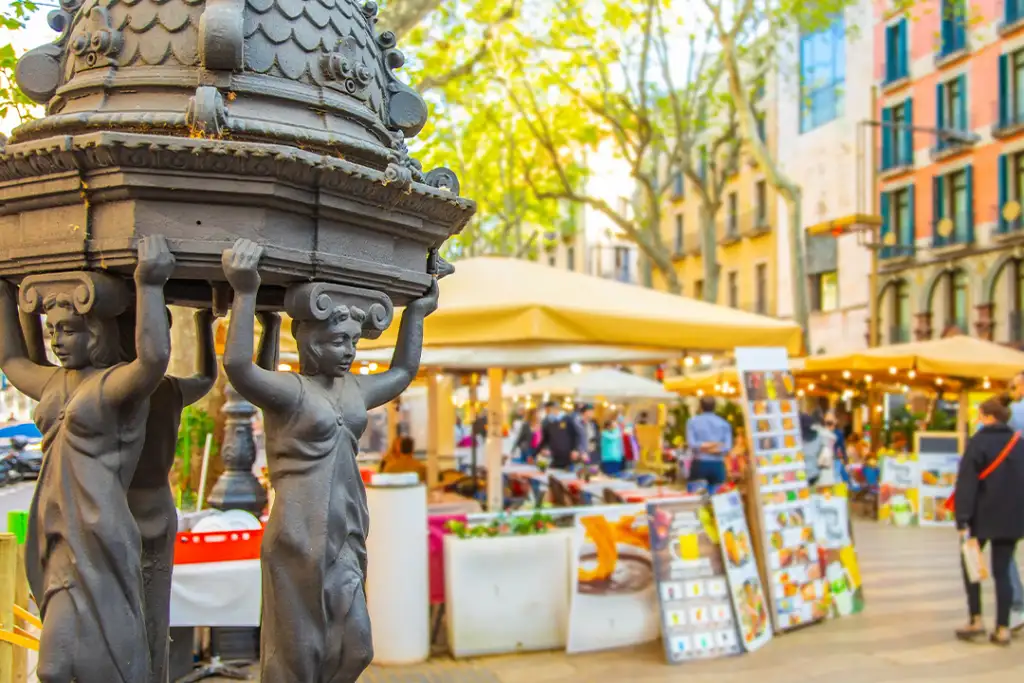 La Rambla most popular pedestrian street in Barcelona. Selective focus on drinking water fountain on foreground.