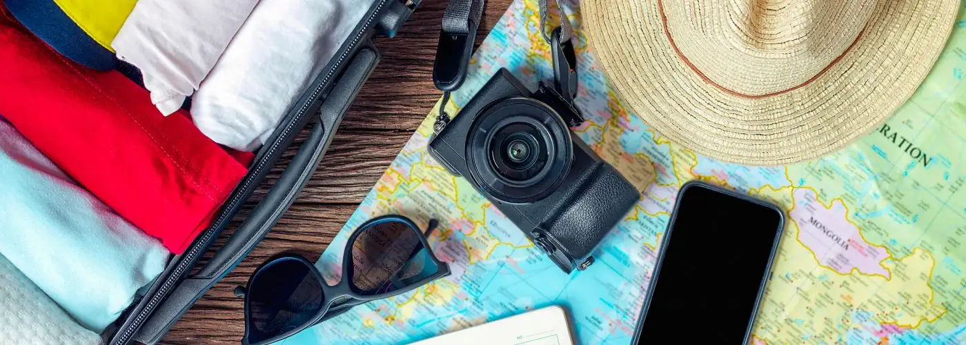 travel items check list camera shoes hat sunglasses and map are displayed on a table