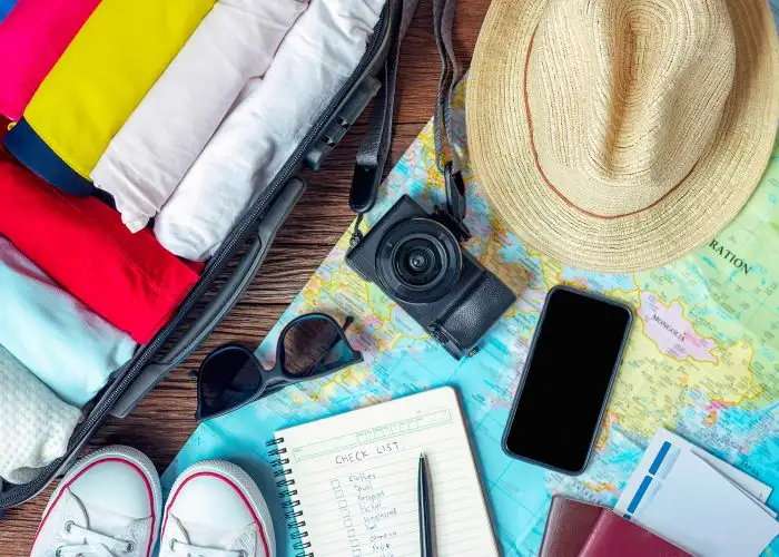 travel items check list camera shoes hat sunglasses and map are displayed on a table