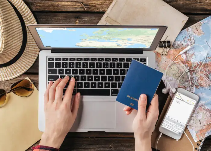 Female hand holding a passport over a laptop