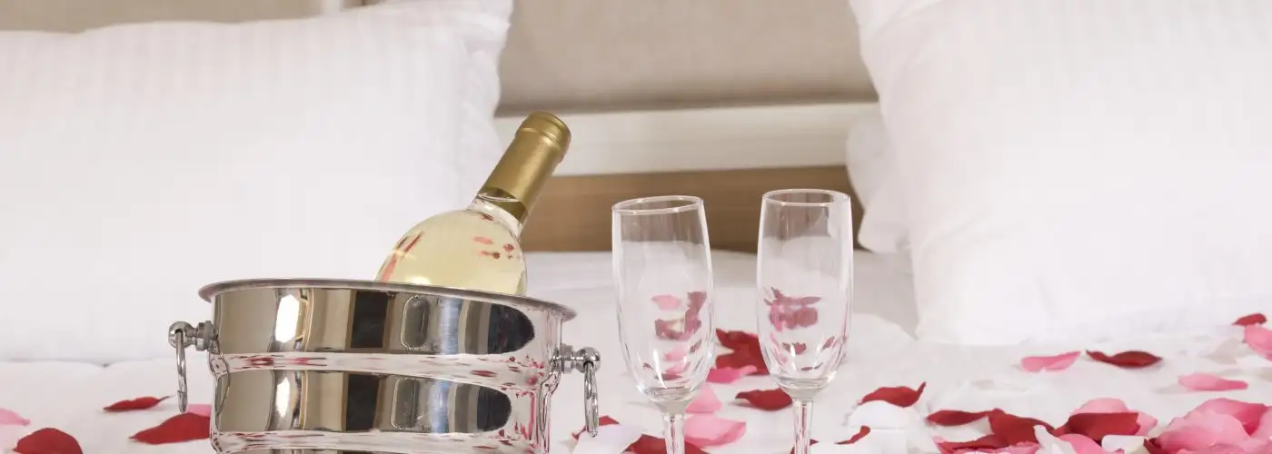 hotel bed with roses and sparking wine