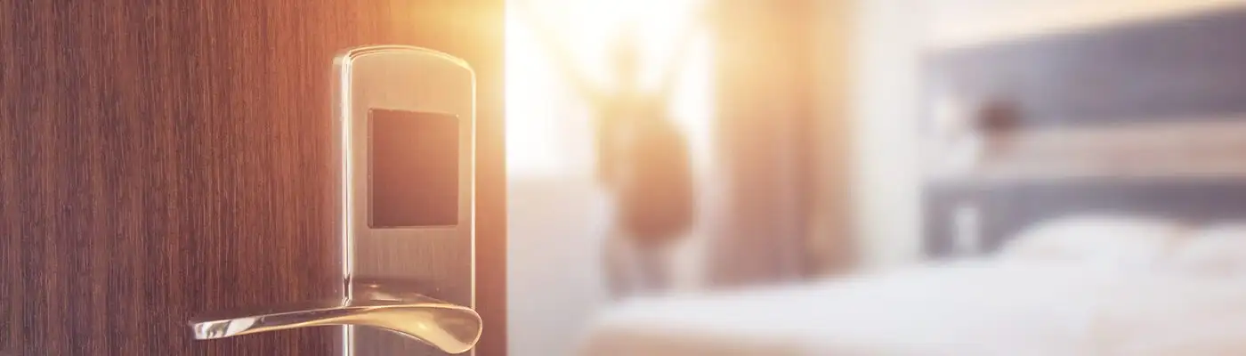 Blurry image of a person opening the curtains of a hotel room as seen from the doorway