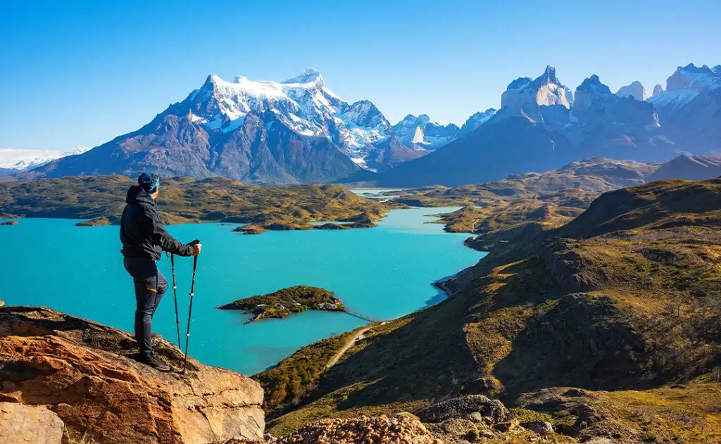 Hiker at mirador condor enjoying amazing view of Los Cuernos rocks and Lake Pehoe in Torres del Paine national park, Patagonia, Chile