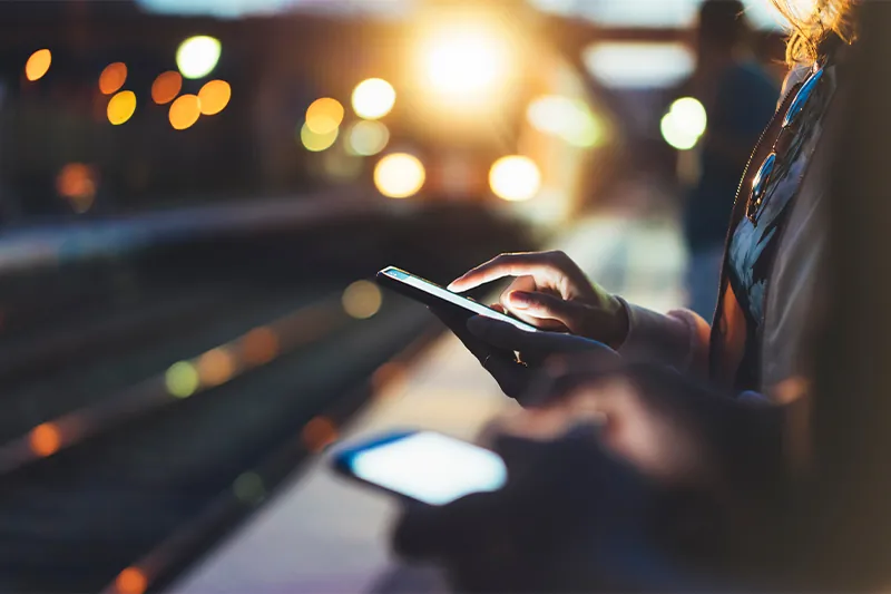 Close up of people using phones at train station at night