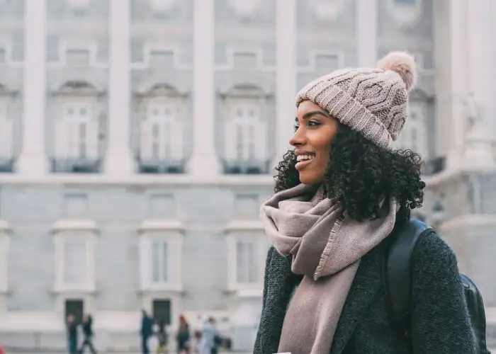 Young black woman drinking coffee wandering in the streets of Madrid on winter tourist